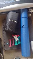 Photo showing black Lixada acupressure mat in carrying bag, blue foam roller, pink, green and teal hand weights, and black interlocking foam mats beneath them.