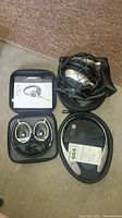 Top view of all three headphone sets with cases and cords, placed on floor