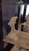 Porcelain dolphin figurine posed jumping with detailed aquatic base and Certificate of Authenticity from Lenox underneath.