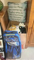 Open box containing decorative throw pillows on top and multiple stuffed animals inside. Adult snorkeling set in front.