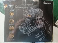 Box front showing AstroAI logo and product features: smart tire inflator, metal motor, LED backlit digital display, LED flashlight.