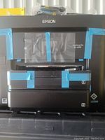 Front view of Epson Workforce Pro EC-4030 printer with protective tape on display and trays.