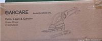 Photo of the original boxed Garcare grass shear, model GCMS02-ETL, with illustration of the tool and brand name visible on package.