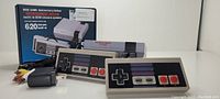 Mini game anniversary edition console box, two controllers, AV cable, and power adapter shown on white surface