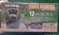 Box front showing Rexing branding and trail camera features like 12-month standby, IP56 water resistance, 0.25 second reaction, triple PIR sensors, wide angle, and automatic temperature compensation.