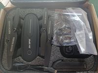 Folded Zuhafa 5G GPS Drone with propellers, camera, charger cable, and spare parts in packing foam.