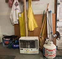 Overview photo showing Campbell Hausfeld air compressor, Kero-Sun Redheat propane heater, propane tanks, rain gear aprons, brooms and brushes against garage wall.