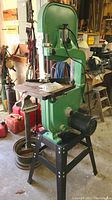 Full front view of green Grizzly band saw on black stand in garage