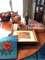 Tabletop display of beaded bag, baskets, prints in frames, wooden bowls, figurine