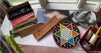 Photo showing assorted vintage board games and toys including Pente, Chinese Checkers, horseshoes, and kites.