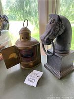 Horse head sculpture and brass nautical lamp side by side