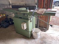 Front-left perspective of full machine showing infeed/outfeed tables and base cabinet