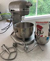 KitchenAid mixer with standard bowl mounted, extra bowl and manual visible