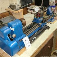 Full view of lathe on bench with headstock, bed, carriage, tailstock and mounted dial indicator