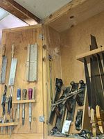 Overview of bench planes and backsaws mounted on wooden board