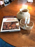 Photo showing two Native American basket books and two woven baskets on a wooden table.