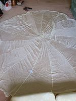 Full view of the laid-out parachute showing circular nylon fabric and attached cords.