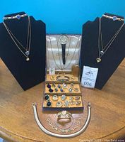 Two display busts showing silver-tone choker with blue heart-shaped stones and layered gold-tone necklaces