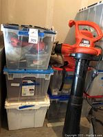 Leaf Hog blower with attached collection bag surrounded by plastic storage bins