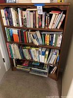 Full front view of the wood 4-shelf bookcase loaded with books