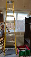 Full view of yellow fiberglass stepladder beside stacked moving dollies