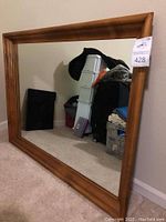 Full view of the large wood framed mirror positioned against wall, showing the frame and reflective surface.