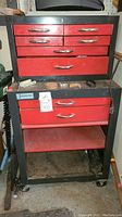 Full view of All American tool chest with red drawers and black framing, visible scratches and wear, on caster wheels.