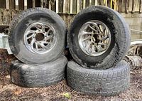 Four 16-inch chrome wheels stacked with mounted tires showing condition and tread wear.