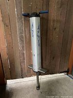 Full view of silver Flybar pogo stick against wooden background showing handle grips, foot pedals, and brand name