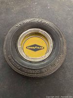 Top view of the vintage Goodyear tire ashtray showing detailed tire tread and inner glass ashtray with Goodyear logo on yellow background.