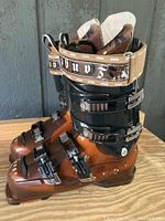 Right side angle view of Lange Banshee Pro men's ski boot showing brown lower shell, black upper cuff, three buckles, and Velcro strap with visible wear.