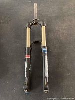 Front view of a black Manitou Nixon mountain bike suspension fork with gold stanchions, showing upper and lower parts and adjustment knob.