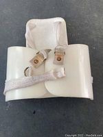 White molded kidney pad featuring fabric straps and leather buckle for securing around the body, showing front side.