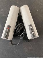 Front view of two Cyber Acoustics multimedia speakers showing logo, volume control knobs, and cables.