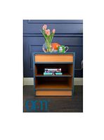 Front view of night stand showing orange drawer front and shelves with blue frame, staged with books and decorative items on top and inside.