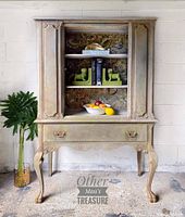 Front view of reimagined vintage china cabinet showing decoupaged back panel, drawer and carved legs