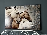 Canvas wall art showing three horses in profile with mixed media background on a gray wall.