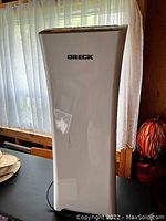 Single photo of tall white Oreck air purifier/humdifier unit with visible logo and power cord