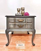 Solid wood vintage side table painted charcoal grey with one drawer and golden hardware, standing on cabriole legs.