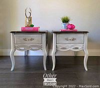 Pair of refinished side tables against wall with staging items on top