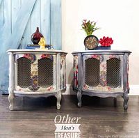 Front view of two painted drum side tables with marble tops and mesh doors.