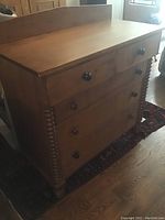 Front view showing four drawers, wooden knob pulls, spiral-turned columns and attached backsplash