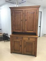 Full front view of two-piece pine hutch showing upper cabinet with two doors and lower base with two drawers and two doors.
