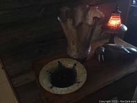 A view showing the clear ruffled top vase behind the art glass bowl on wooden surface in dim lighting