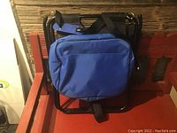 Folded foldable chair with attached bright blue soft-sided cooler bag, showing entire unit compact and flat.