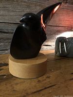 Front view of black stone hawk sculpture on round wood base