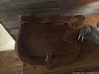 Front view of brown Orvis leather satchel bag with buckle closure and embossed Orvis logo.