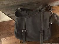 Front view of slate grey leather Roots messenger bag with two buckle straps and adjustable shoulder strap.