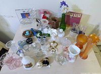 Wide view of lot showing milk glass bell, vases, glassware, shot glasses and various decorative items