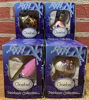 Four Goebel ornaments in original blue-purple boxes with snowflake design, front view.